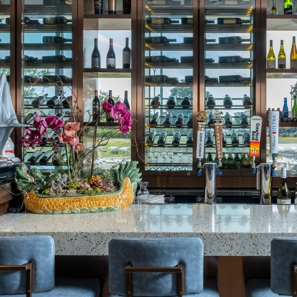 Modern bar with a speckled countertop, blue stools, beer taps, and a wine display wall.